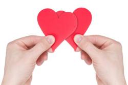 Hands holding two red paper hearts